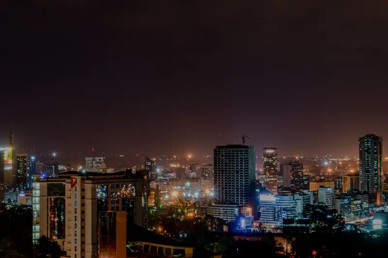 Un horizon de ville la nuit, les tours éclairées au-dessus des quartiers.