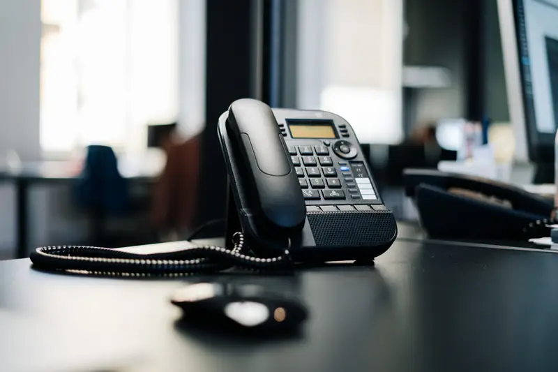 Un téléphone de bureau posé sur un plan sombre.